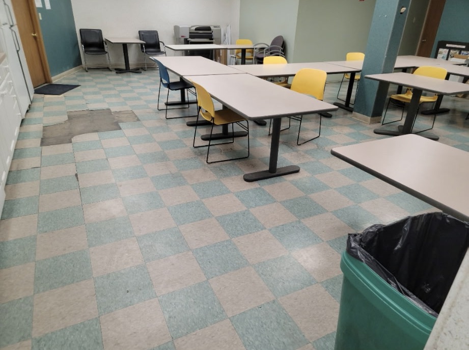 Worn green and grey VCT tile floor in a commercial break room before coating