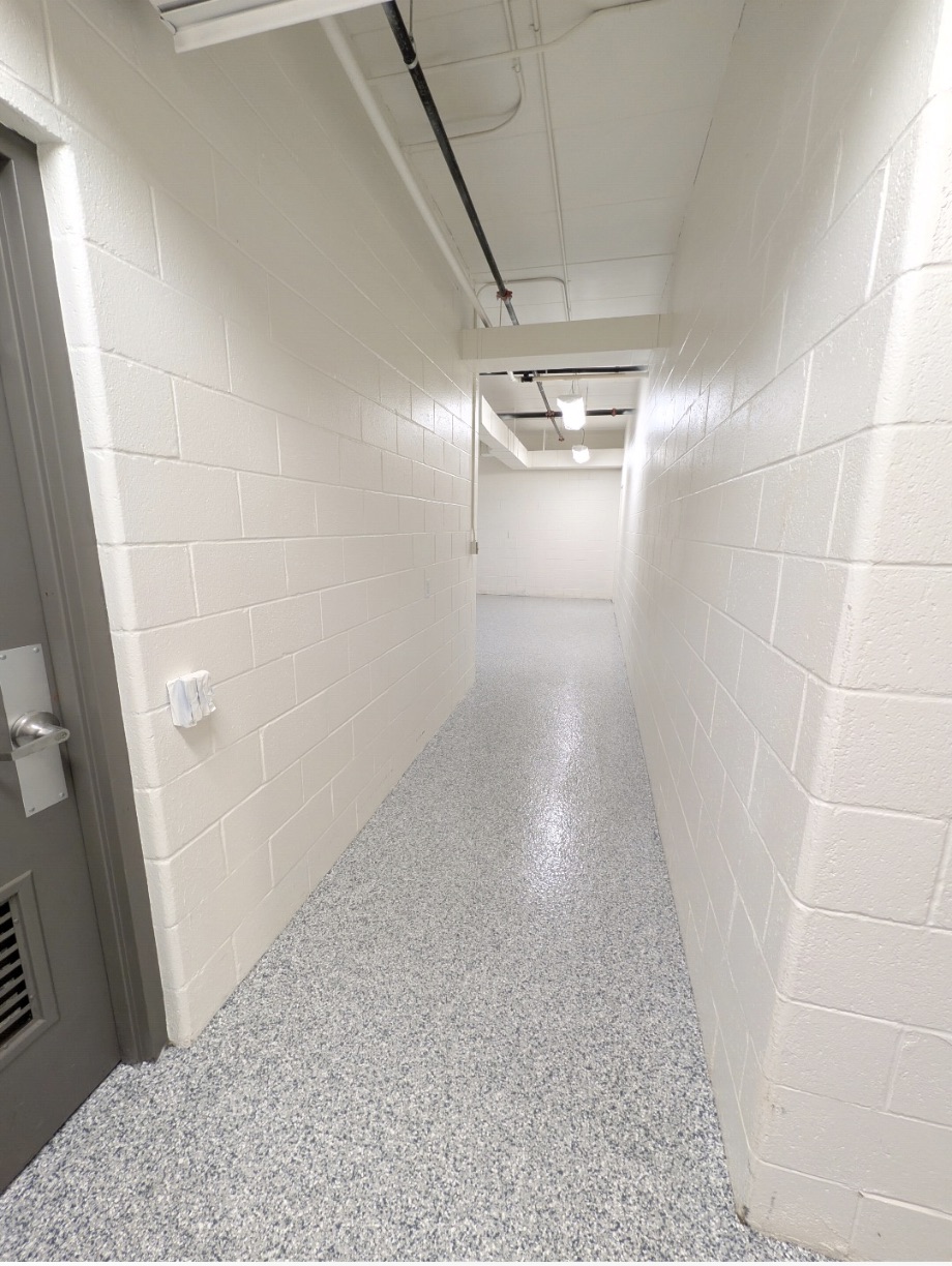 Speckled flake epoxy floor coating running down a white block hallway