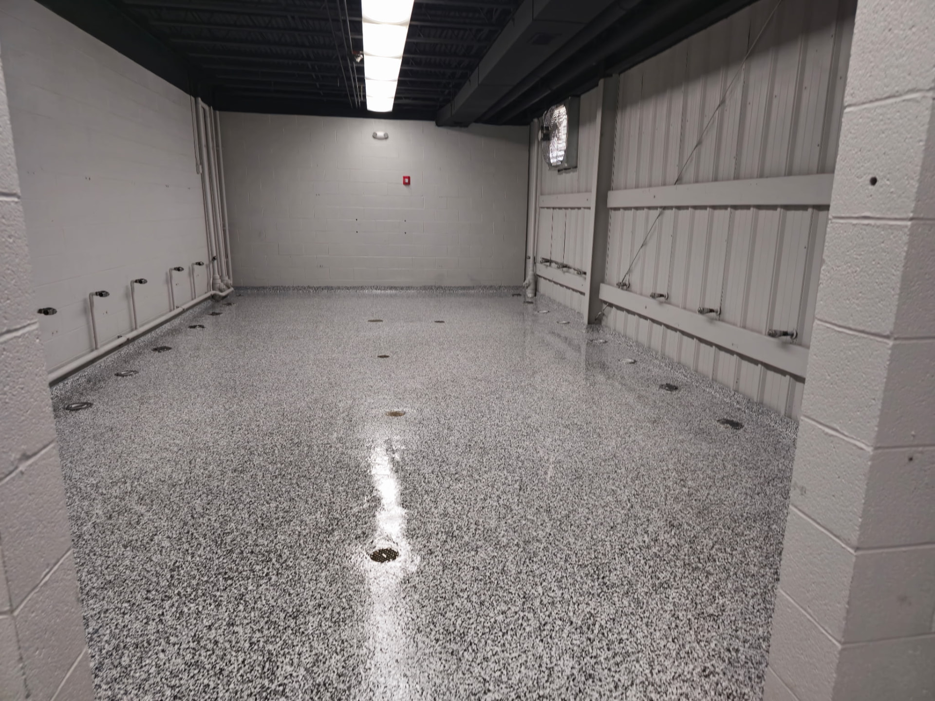 Glossy black and white flake epoxy floor in a commercial utility room